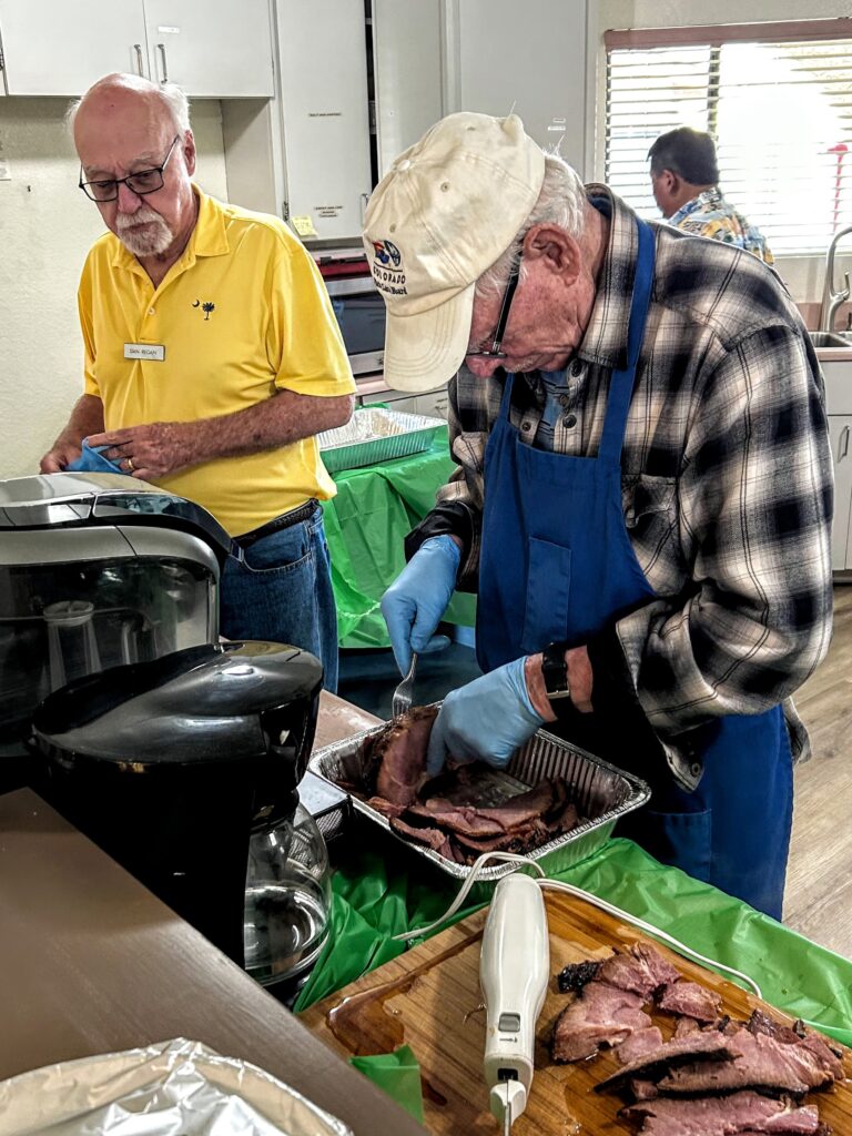 Dan Regan checks with Phillip Young about how soon the slices of ham will be ready to take out to the serving line.